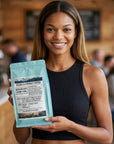 Woman holding a package of Selden & Kingley Coffee in a coffee shop setting
